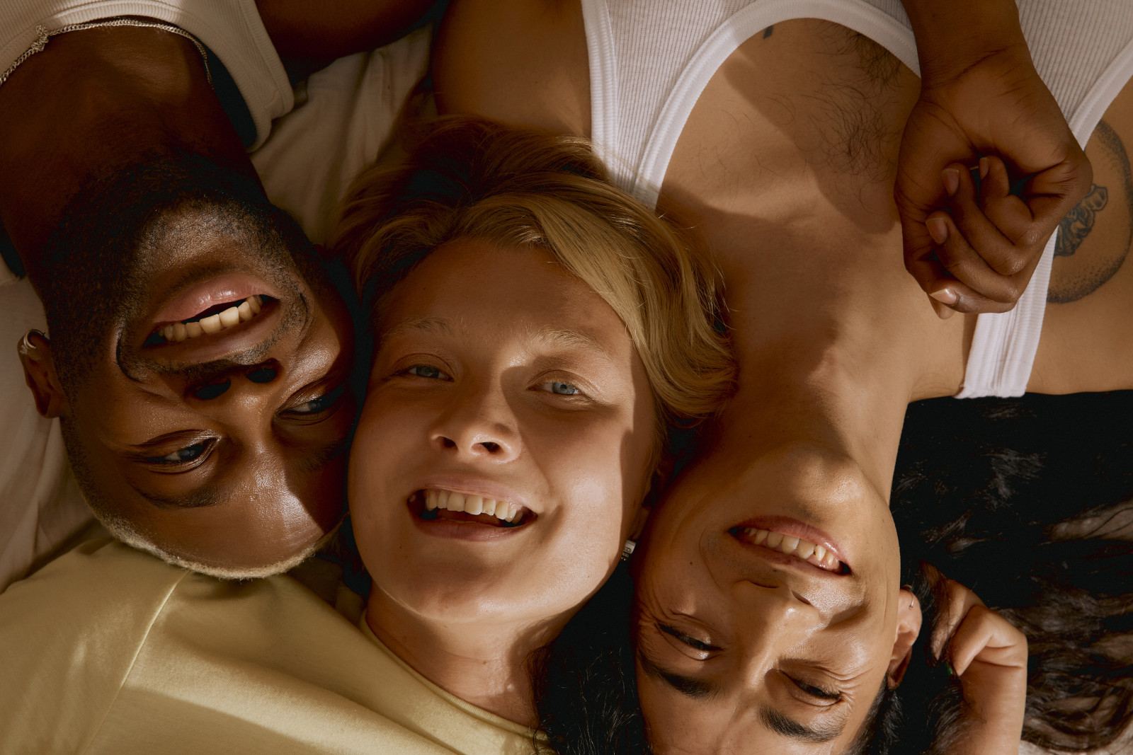 Three friends lying head to head, laughing